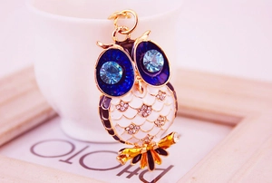 Détail du pendentif hibou avec yeux en cristal bleu et motif en émail blanc