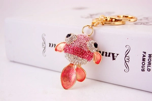 Détail du porte-clés poisson rouge avec strass roses et fermoir en métal doré sur livre