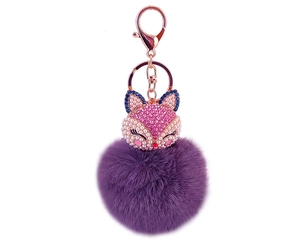 Close-up of purple fur pompom keychain featuring a pink rhinestone fox head and gold clasp
