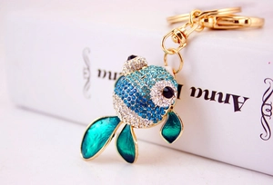 Vue macro du porte-clés poisson rouge doré avec strass bleus et nageoires en émail vert