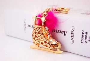 Détail du porte-clés patin à glace doré avec strass et pompon en fourrure rose