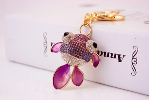 Détail de porte-clés poisson rouge avec strass violets et fermoir en métal doré