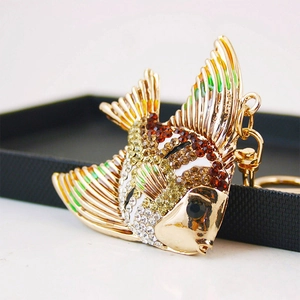 Porte-clés poisson tropical doré orné de strass colorés sur un présentoir noir