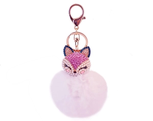 Close-up of rose gold keychain with rhinestones fox head and soft pink fur pom-pom ball