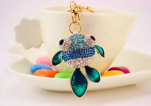 Vue détaillée d'un porte-clés poisson bleu avec nageoires vertes sur une tasse blanche