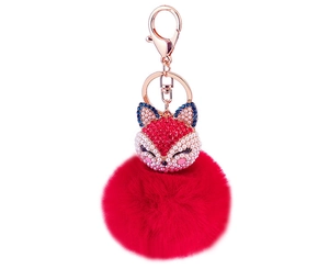 Detail of red fur pompom keychain with fox head inlaid in crystals and pearls