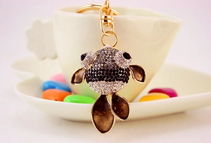 Gros plan d'un porte-clés poisson rouge avec strass brillants accroché à une tasse blanche