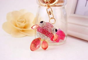 Détail macro du porte-clés poisson rouge avec strass roses et finition émail