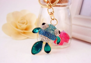 Détail d'un porte-clés poisson rouge avec strass bleus et fermoir doré pour sacs