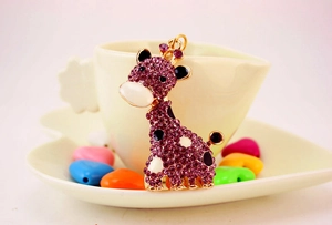 Détail d'un porte-clés girafe doré avec strass violets sur une assiette décorative