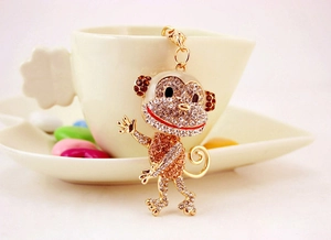 Macro shot of a sparkling rhinestone-encrusted monkey keychain on a ceramic cup rim