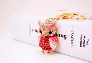 Detail of owl keychain with rose pink crystals and enamel finish on a book spine