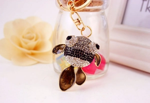 Détail d'un porte-clés poisson rouge avec strass noirs et blancs sur métal doré brillant