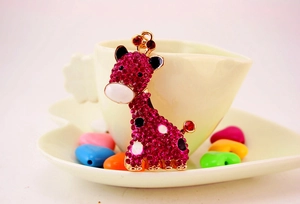 Détail du pendentif girafe avec strass roses, base en métal doré et émail coloré