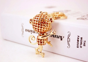 Detailed side view of golden monkey keychain with heart cutouts on a book prop
