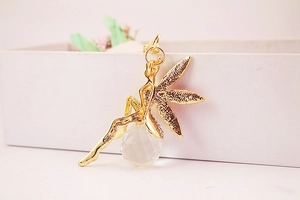 Gros plan d'un pendentif fée dorée avec ailes texturées et sphère en cristal facetté