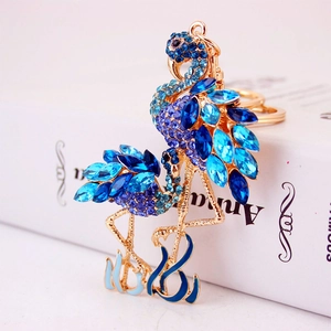 Porte-clés flamant rose en cristal bleu avec métal doré posé sur un livre blanc pur