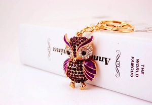 Detail of owl keychain with purple enamel and sparkling crystal rhinestones in golden finish