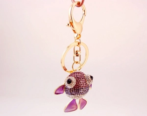 Détails d'un porte-clés poisson rouge avec strass violets et finition métal doré