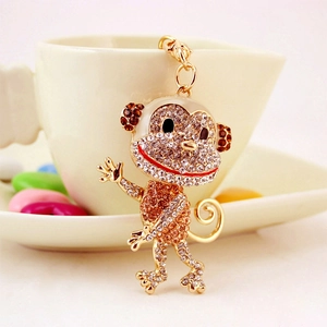 Cute monkey keychain with sparkling rhinestones hanging on a white coffee cup