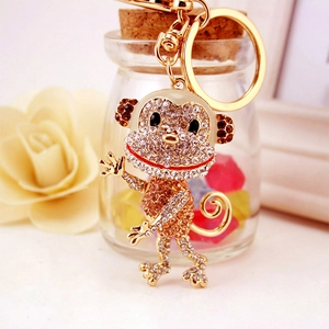 Sparkling crystal monkey keychain with rhinestones and gold-plated metal link on light surface