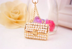 Detail of elegant pearl encrusted handbag charm with gold metal frame and chain