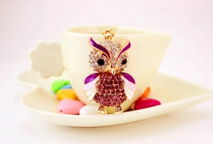 Detailed owl keychain with purple crystals and enamel finish on a ceramic cup