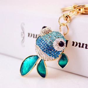 Porte-clés poisson rouge étincelant avec strass bleus et émail vert sur présentoir