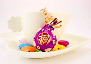 Detail view of purple money bag keychain with crystal accents and lucky symbol