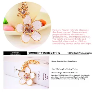 Detailed close-up of golden daisy keychain with white enamel petals and colorful rhinestones