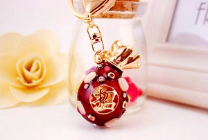 Macro view of lucky fortune bag keychain with red enamel and sparkling crystal inlay