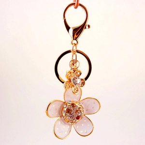 Golden flower keychain with white enamel petals and rhinestones for women's bags