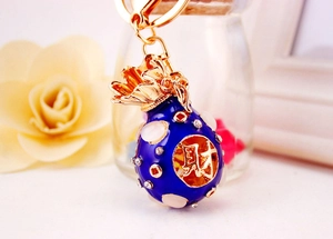 Detailed close-up of dark blue lucky money bag keychain with crystal inlays and golden coin