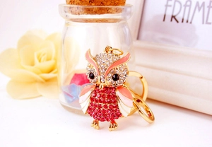 Detailed macro view of a crystal-encrusted owl keychain with pink enamel and gold hooks