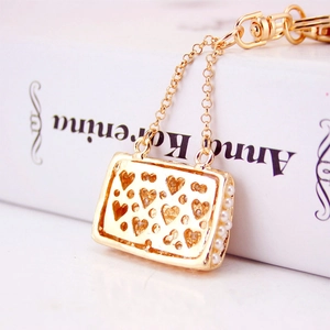 Golden handbag keychain with heart cutouts, sparkling crystals and pearl trim chain