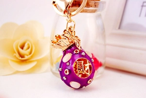 Close-up of purple enamel money bag keychain with gold heart clasp and rhinestones