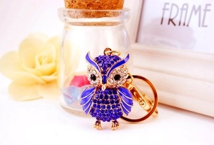 Close-up of golden owl keychain with blue rhinestones, enamel wings and lobster clasp