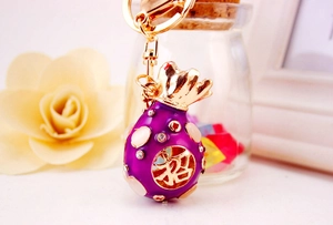 Detail of a sparkling purple money bag keychain with gold accents and rhinestones