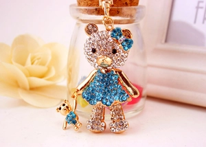 Dettaglio macro del portachiavi a forma di orso con strass, vestito blu e catena dorata