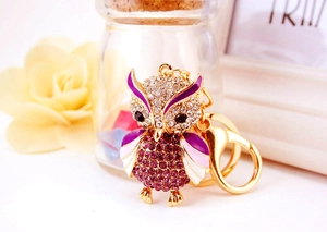 Detailed shot of an owl keychain with purple crystals and gold alloy lobster clasp