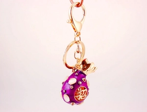Detailed view of purple fortune bag keychain with gold plating and sparkling crystals