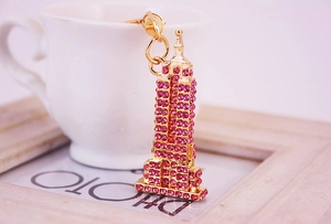 Detail van een gouden Eiffeltoren sleutelhanger met roze strass naast een koffiekop