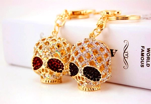 Détail d'un porte-clés crâne doré serti de strass brillants avec des yeux en pierre rouge