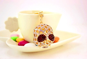 Détail du porte-clés crâne en cristal avec yeux en strass rouges suspendu à une tasse blanche