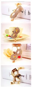 Detail view of crystal rhinestone mask keychain with a brown teardrop pendant in golden plating