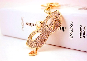 Detail of masquerade mask keychain with sparkling crystals and yellow gemstone drops