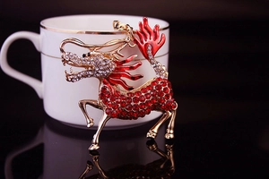 Detail of a gold kirin keychain with red crystals and drip oil finish on a mirrored surface