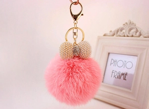 Detailansicht pinker Plüsch-Schlüsselanhänger mit Perlenbogen und goldenem Karabiner