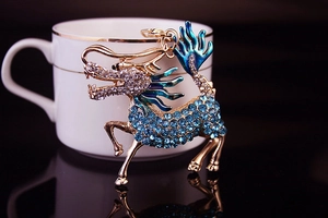 Detailed close-up of blue rhinestone Kirin keychain with teal enamel on gold metal base
