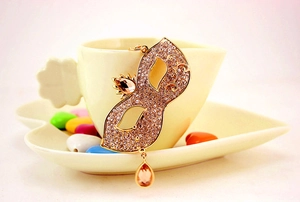 Detail of golden mask keychain with sparkling rhinestones and champagne drop pendant